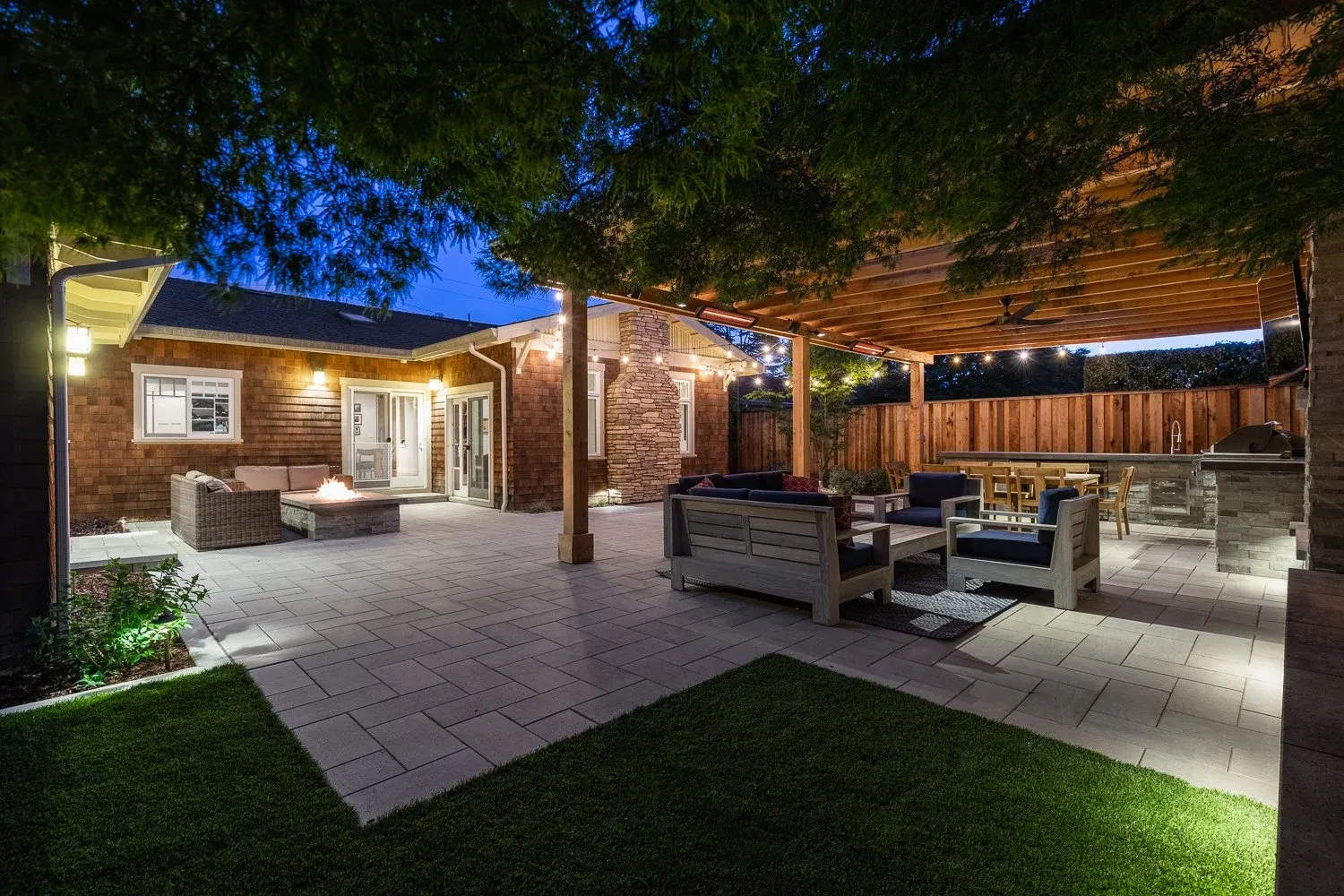 Backyard lounge beside a lawn, lit at dusk