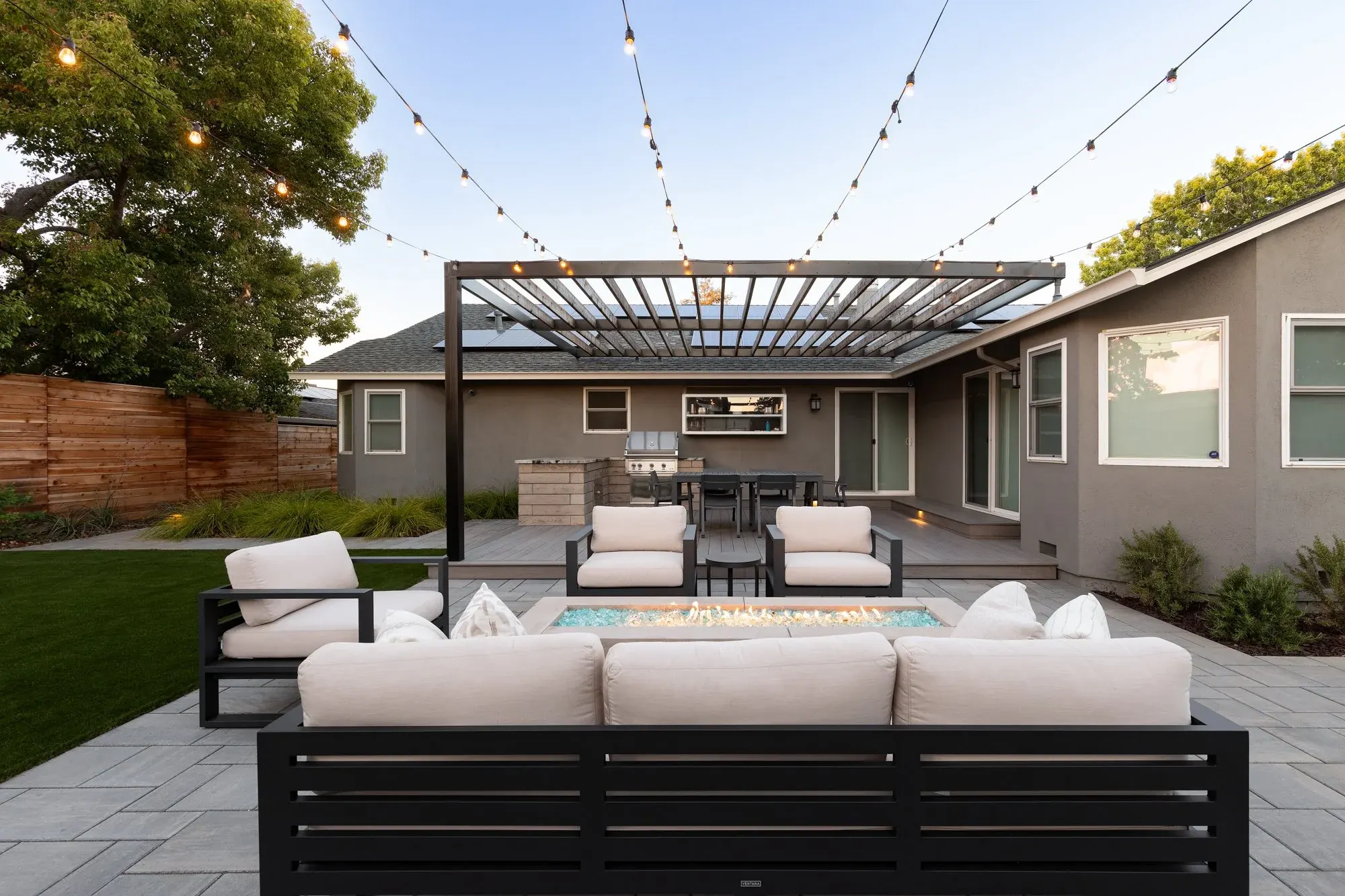 Backyard lounge with a fire table under a wood pergola