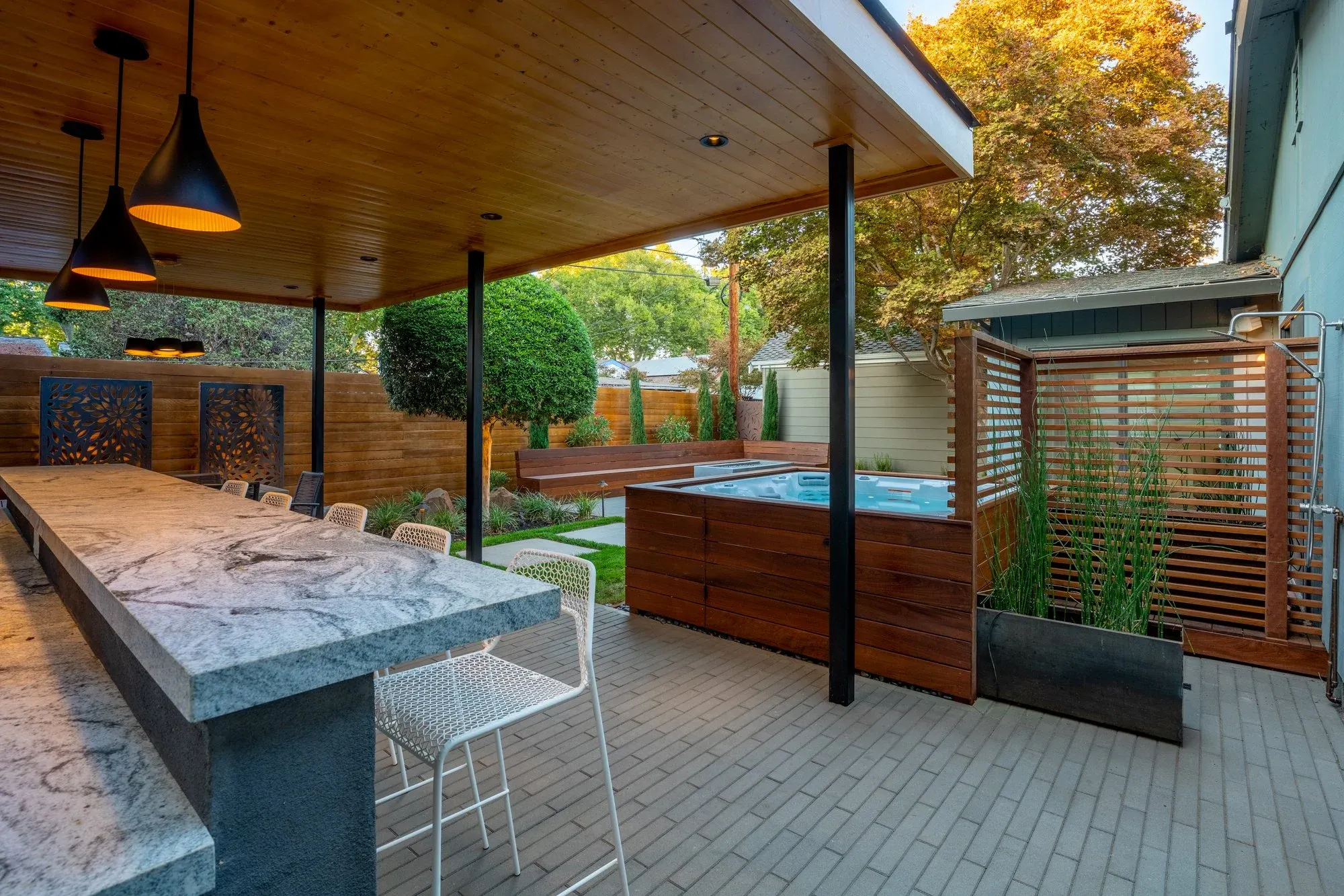 Covered bar with a stone counter and pendant lights
