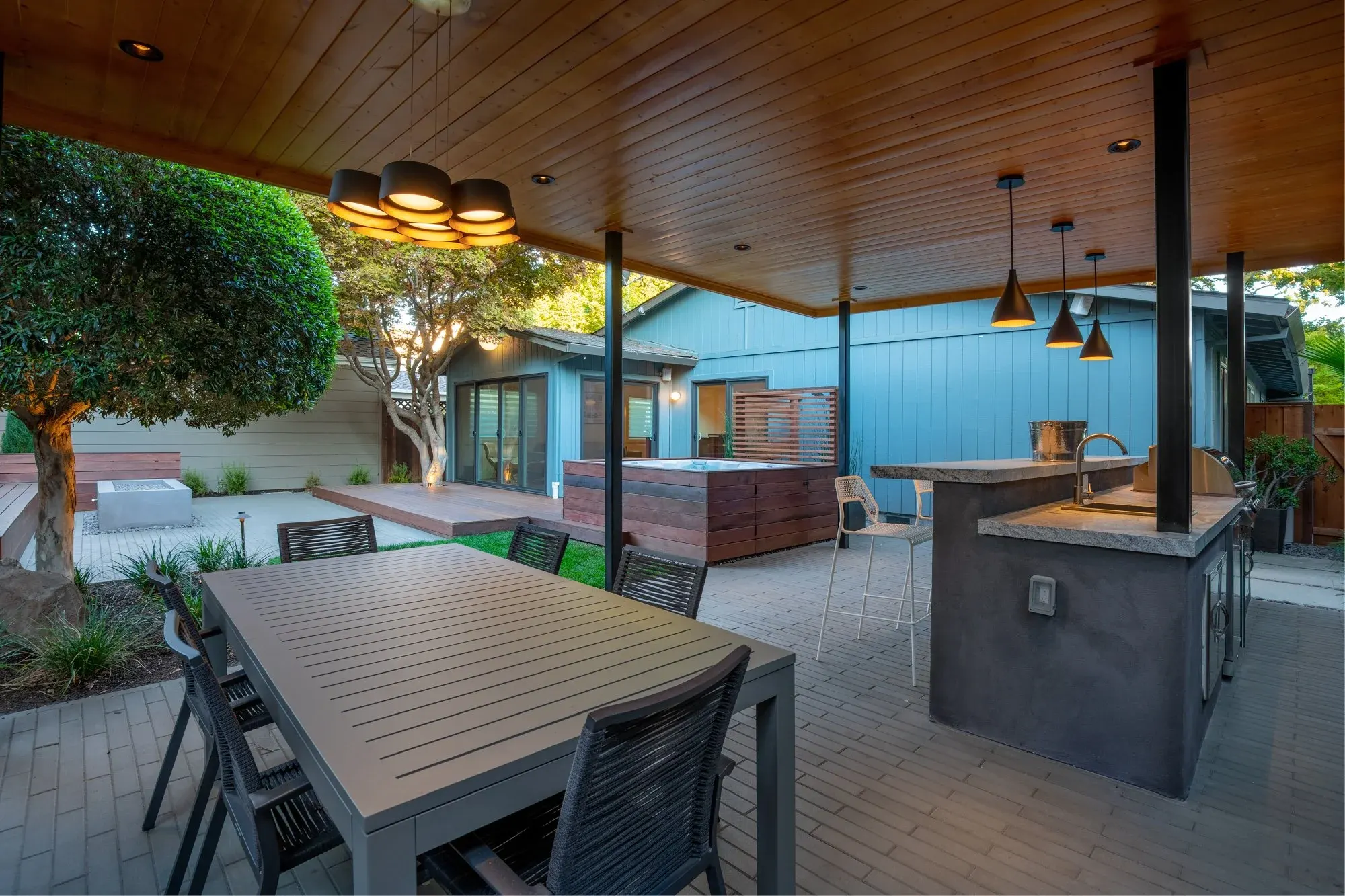Dining table under a covered kitchen with pendant lights