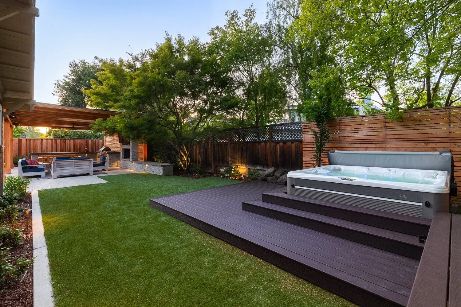 Dark wood deck with a hot tub beside a lawn