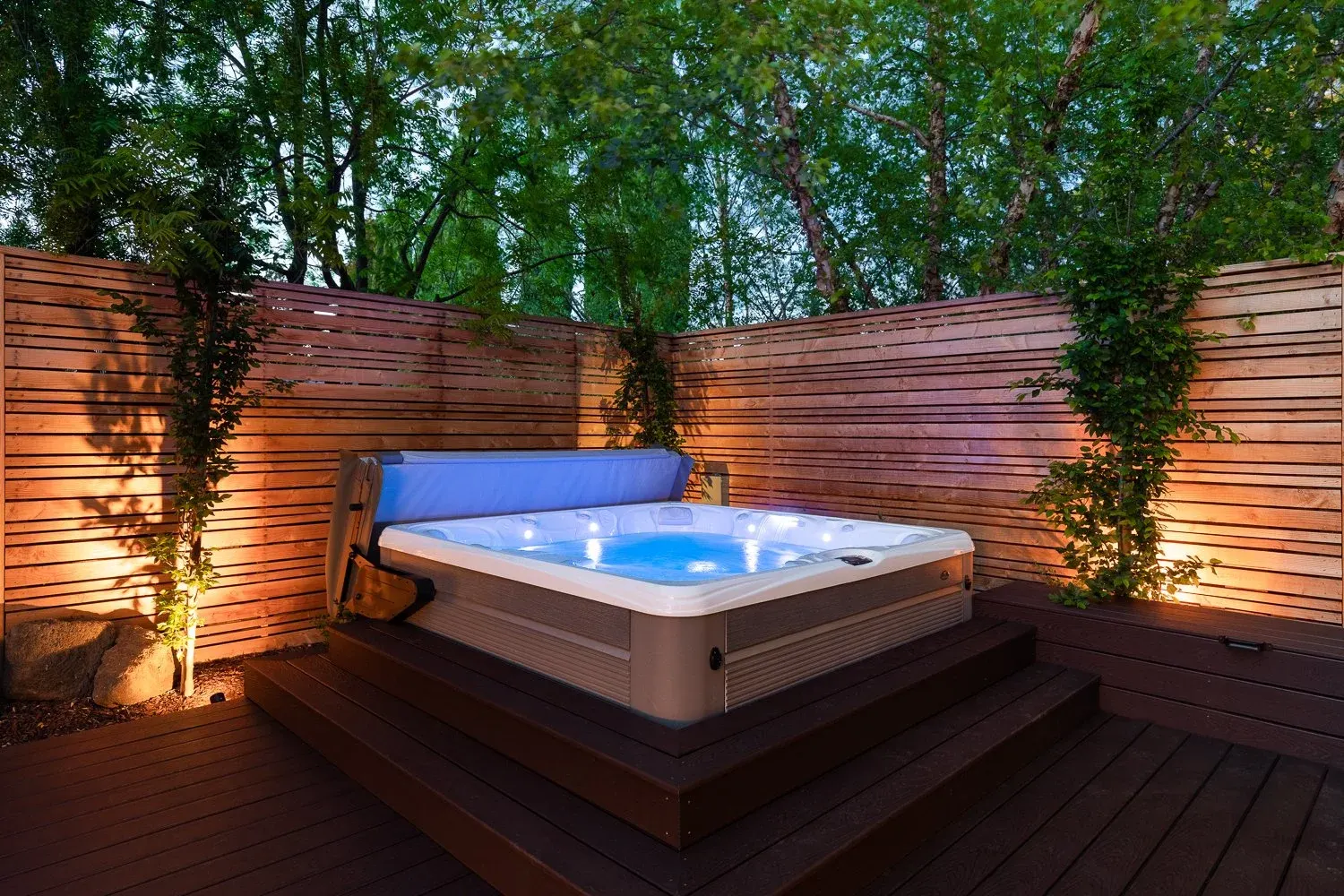 Hot tub on a dark deck behind horizontal cedar screens
