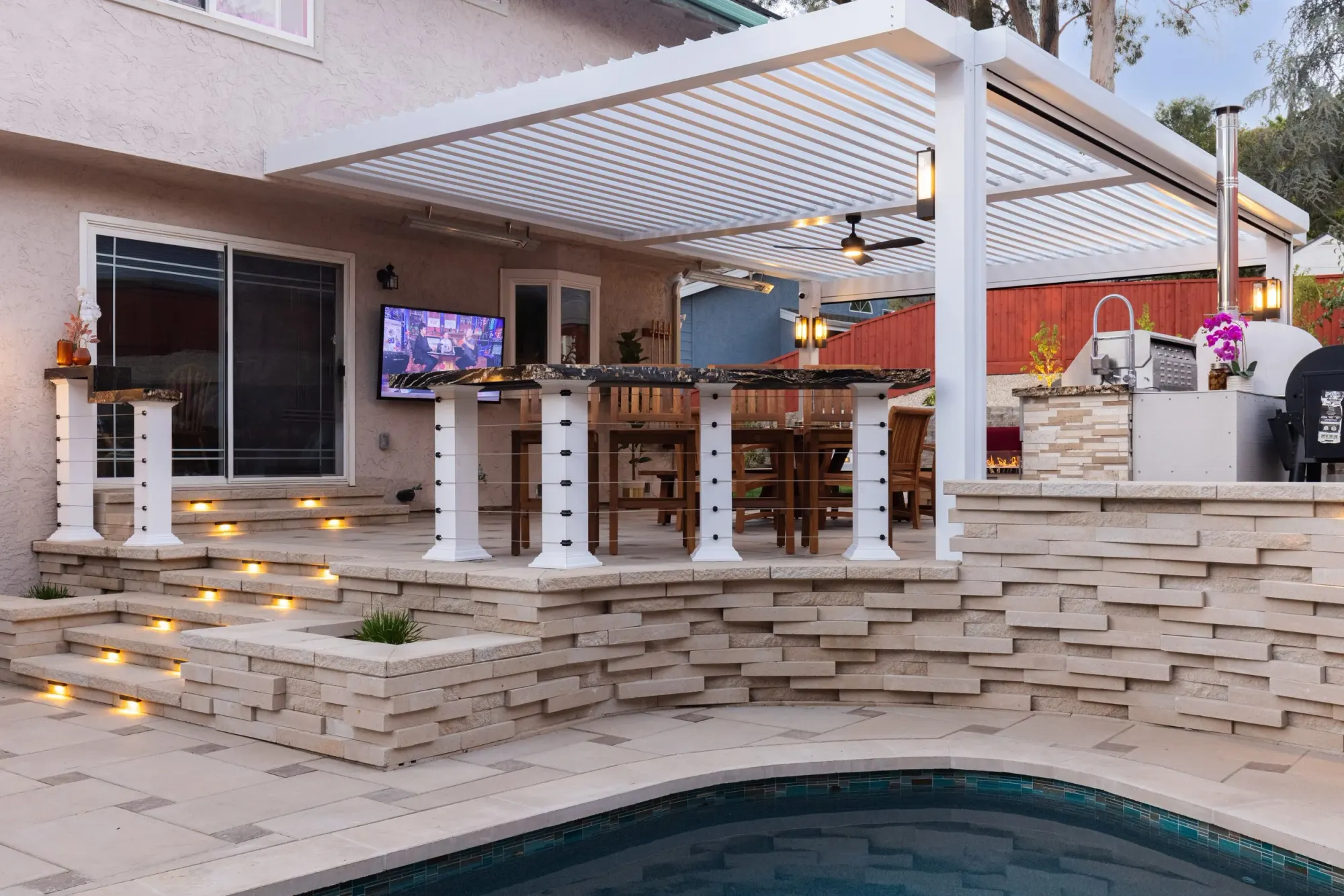 Lit stone steps under a louvered cover beside a pool