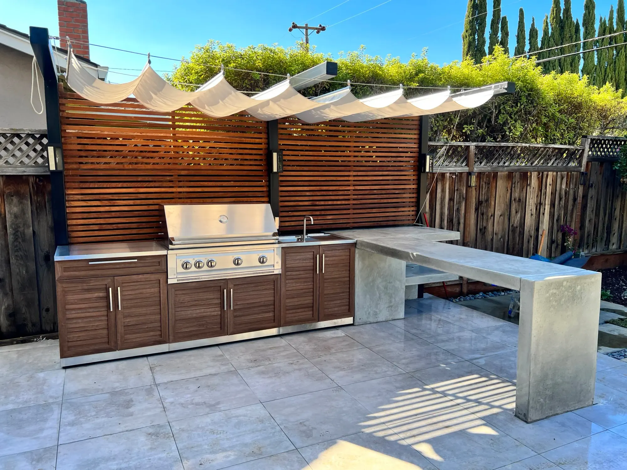 Outdoor kitchen with a wood-slat screen behind it
