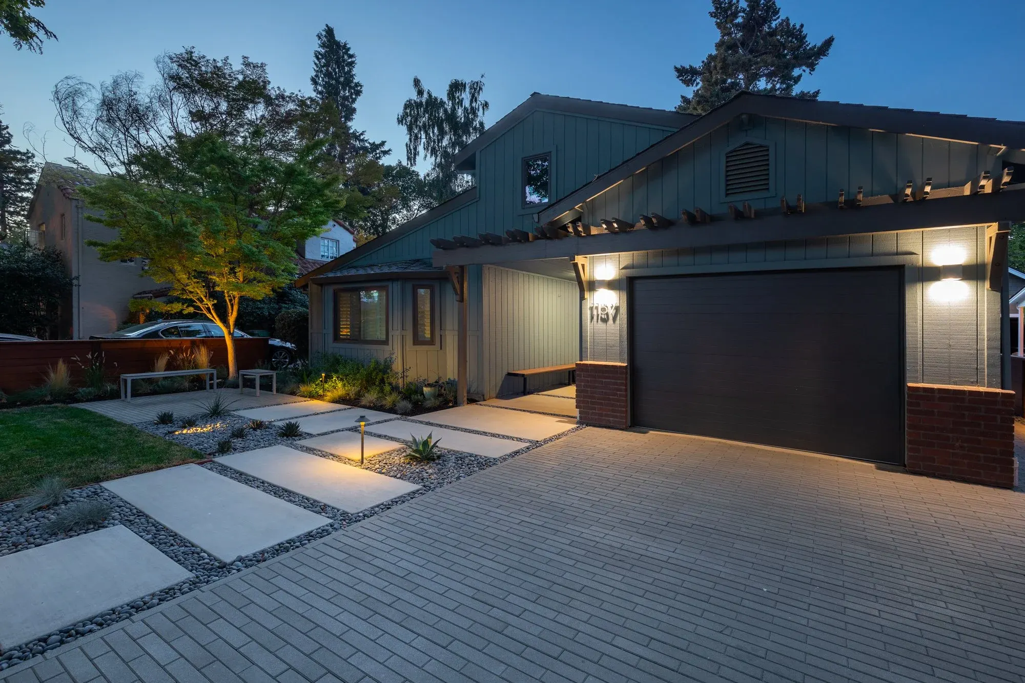 Paver driveway and concrete slab walk lit at dusk