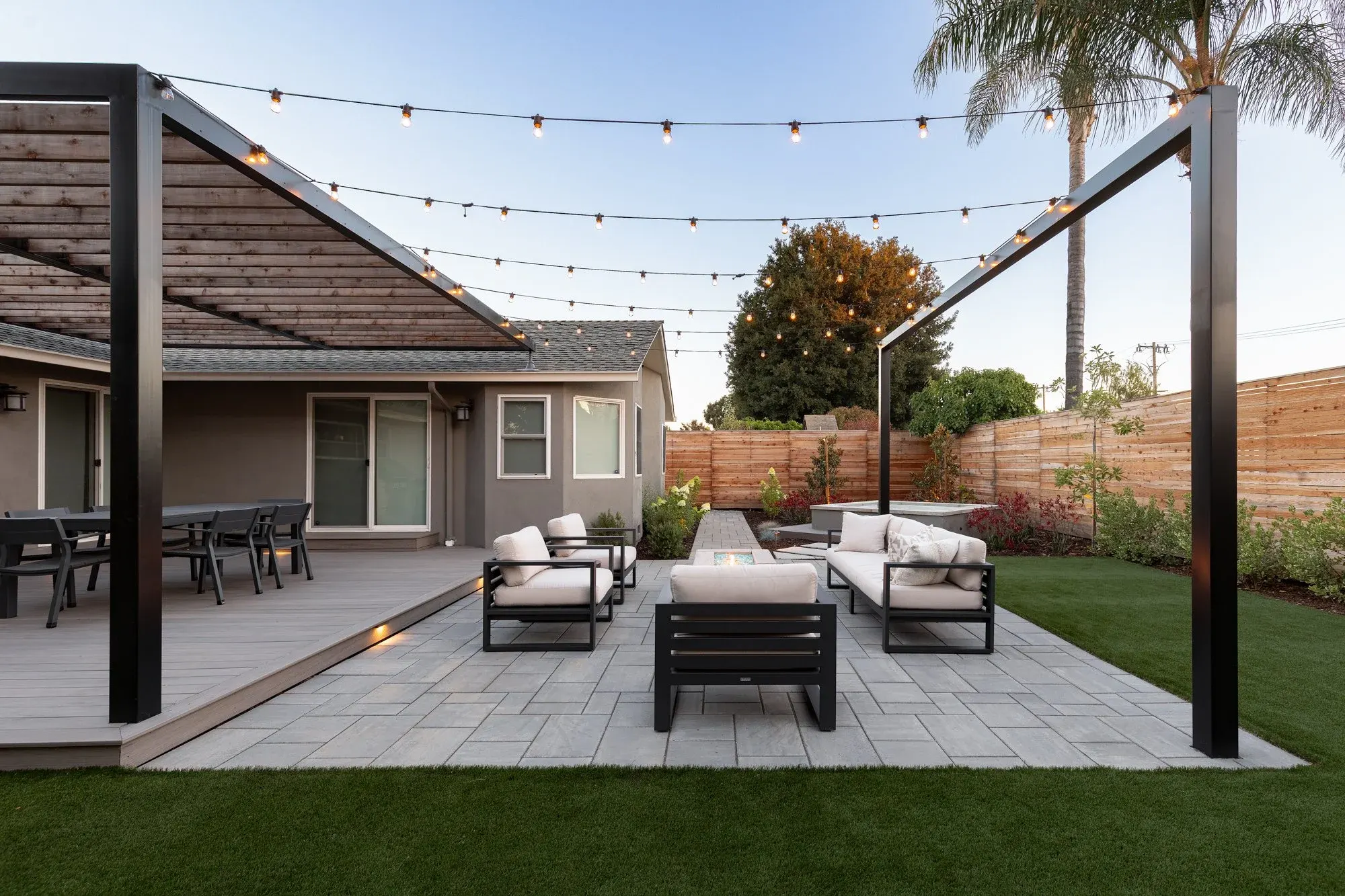 Paver patio lounge under string lights on steel posts