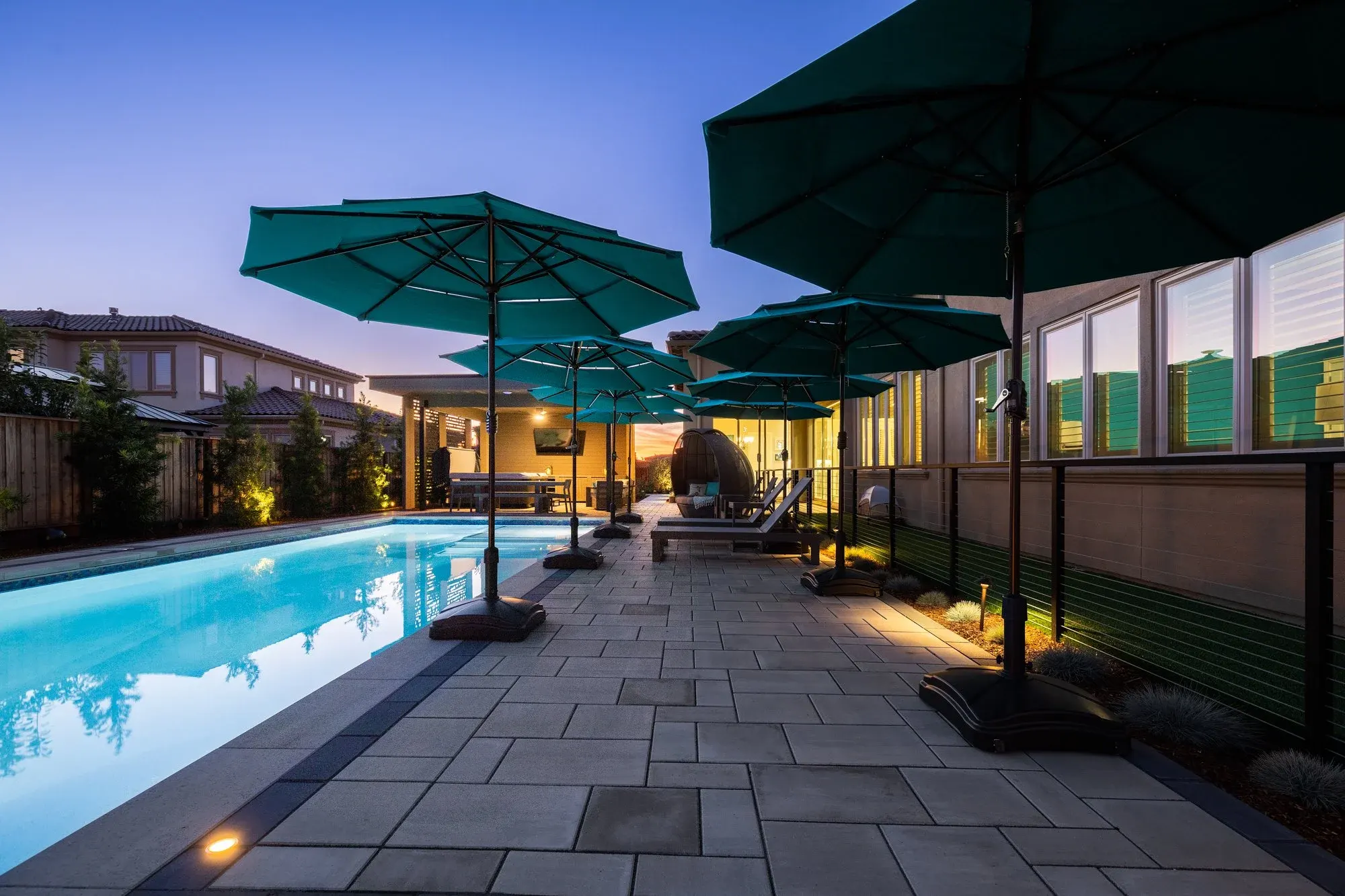 Pool and paver terrace with umbrellas at twilight