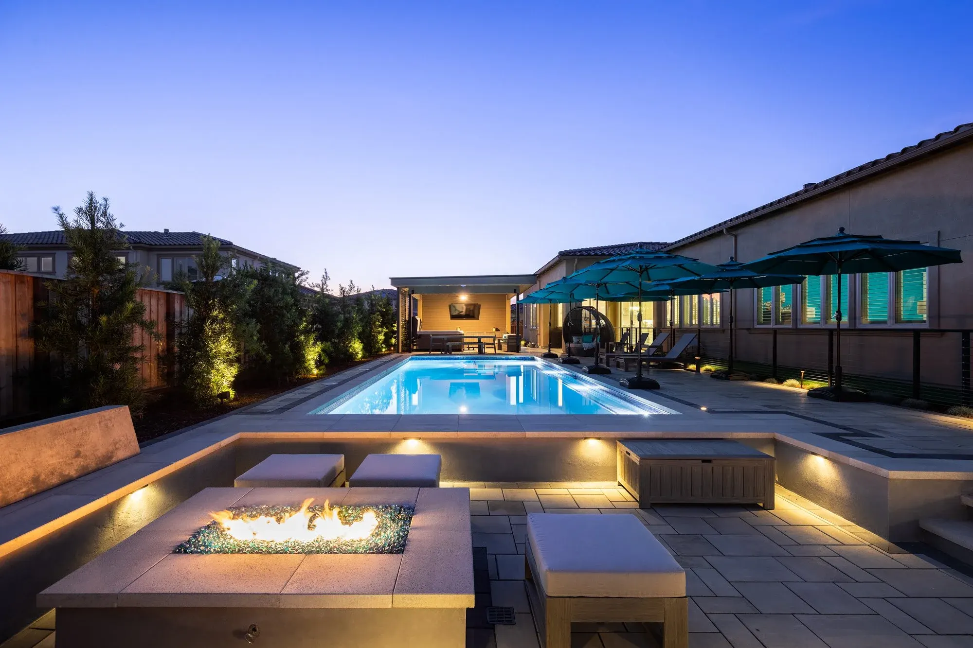 Pool deck with a fire table, lit at dusk
