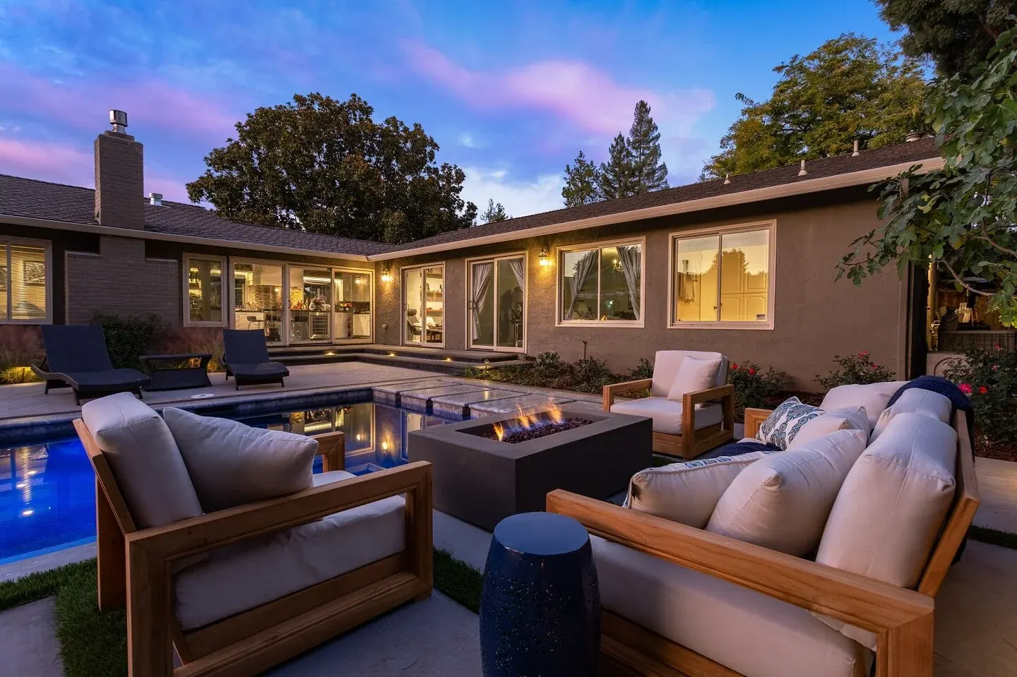 Pool terrace with a fire feature, lit at dusk
